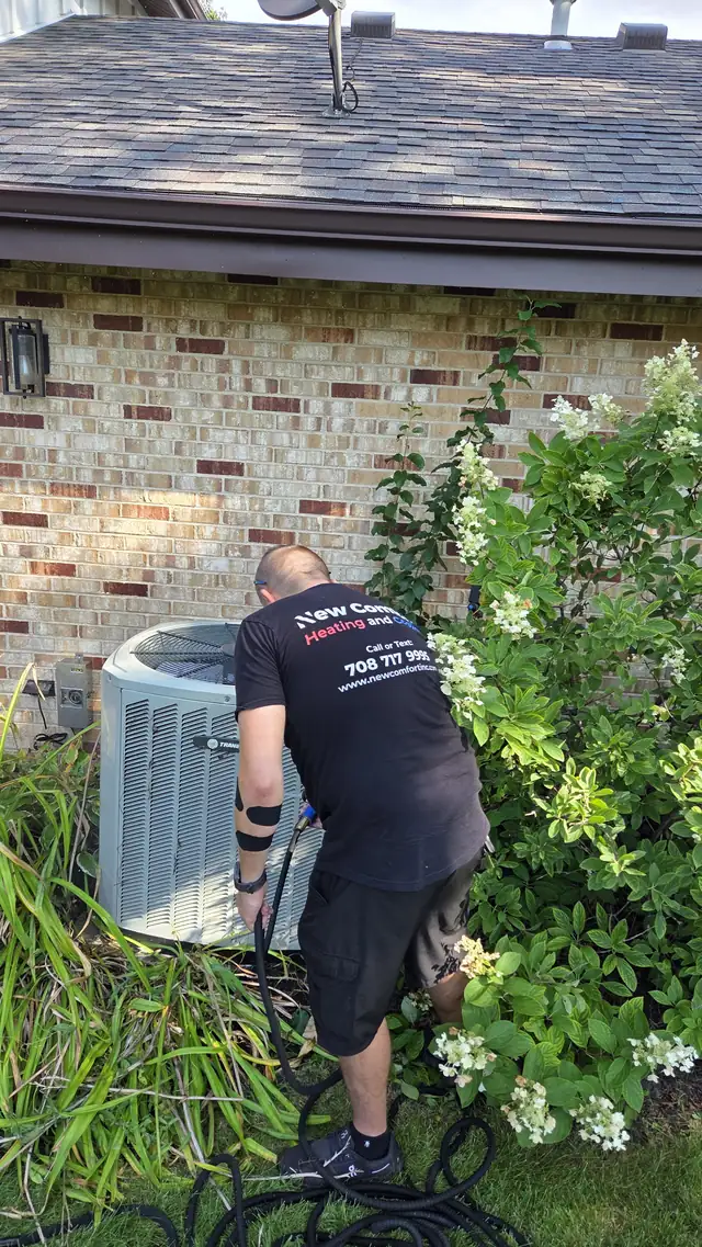 New Comfort technician cleaning an outdoor air conditioner