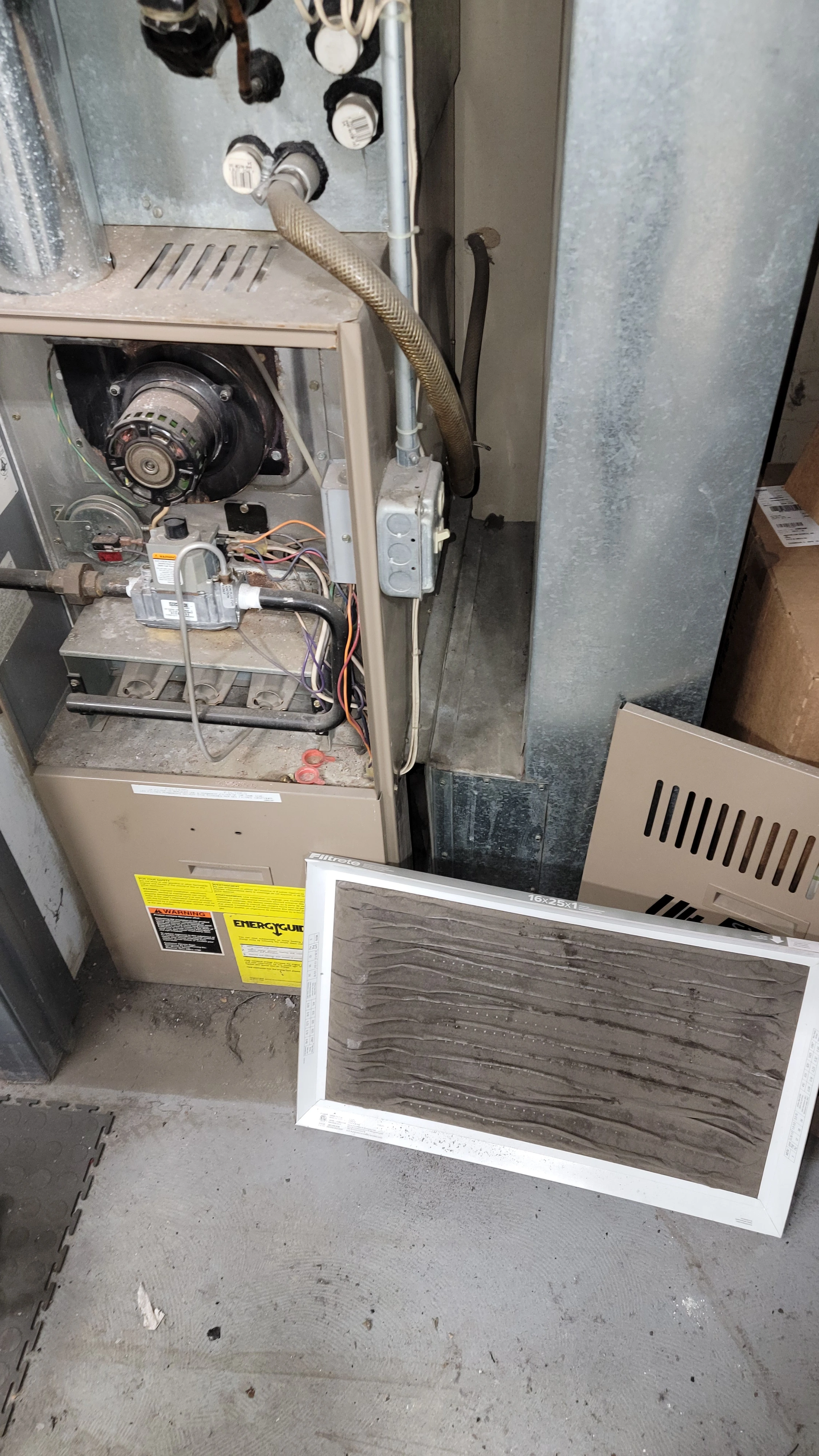 Older furnace with a dirty air filter removed during an inspection