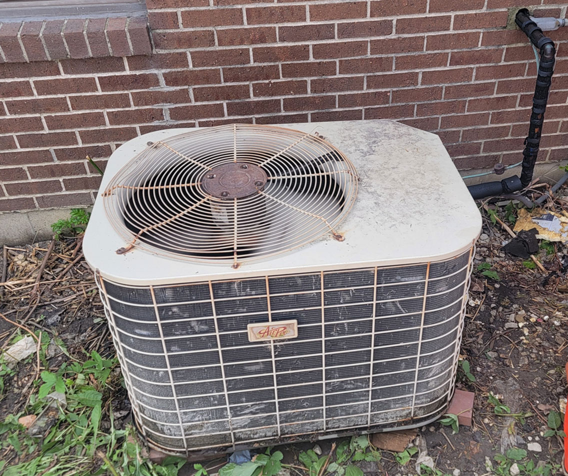 Aging, rust-stained AC condenser near the end of its life, photographed before replacement