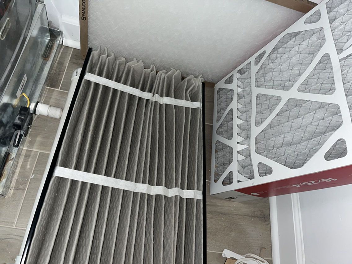 Media air filter being replaced in a furnace cabinet during HVAC system maintenance